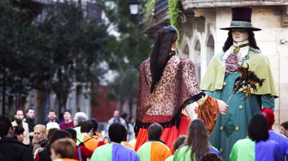 Figuras y participantes disfrazados desfilando en una rúa de Carnaval por las calles de Barcelona.