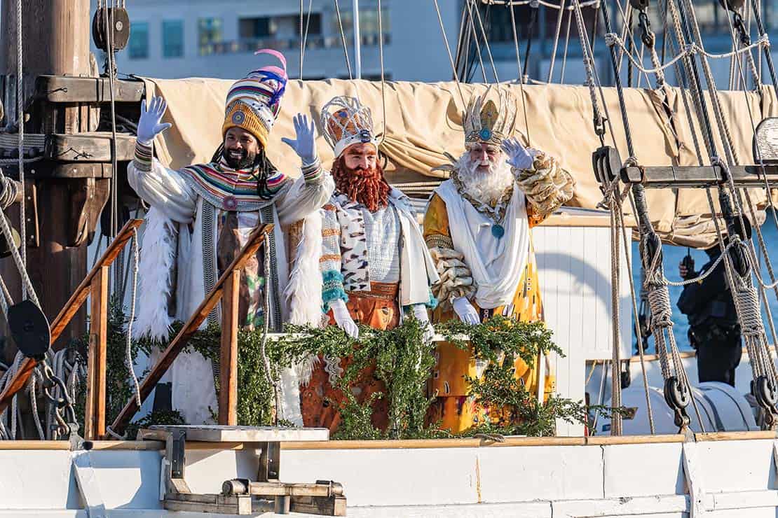 Los Reyes Magos saludando al público desde un barco durante la llegada por mar en Barcelona.