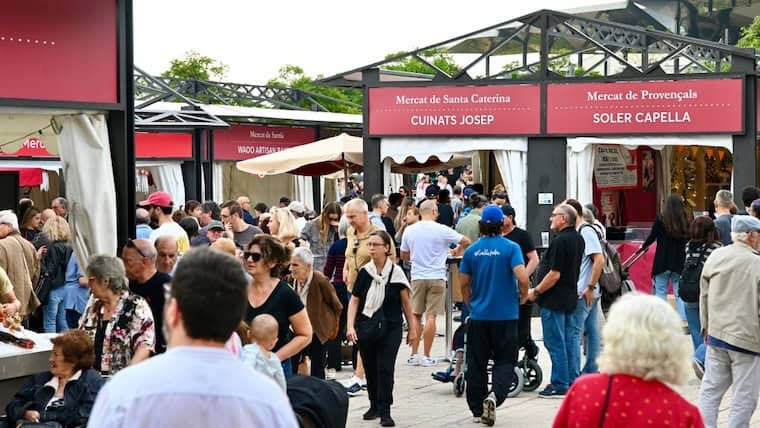 Ambiente concurrido en la Feria del Comercio Local de Barcelona con puestos de comida y visitantes.