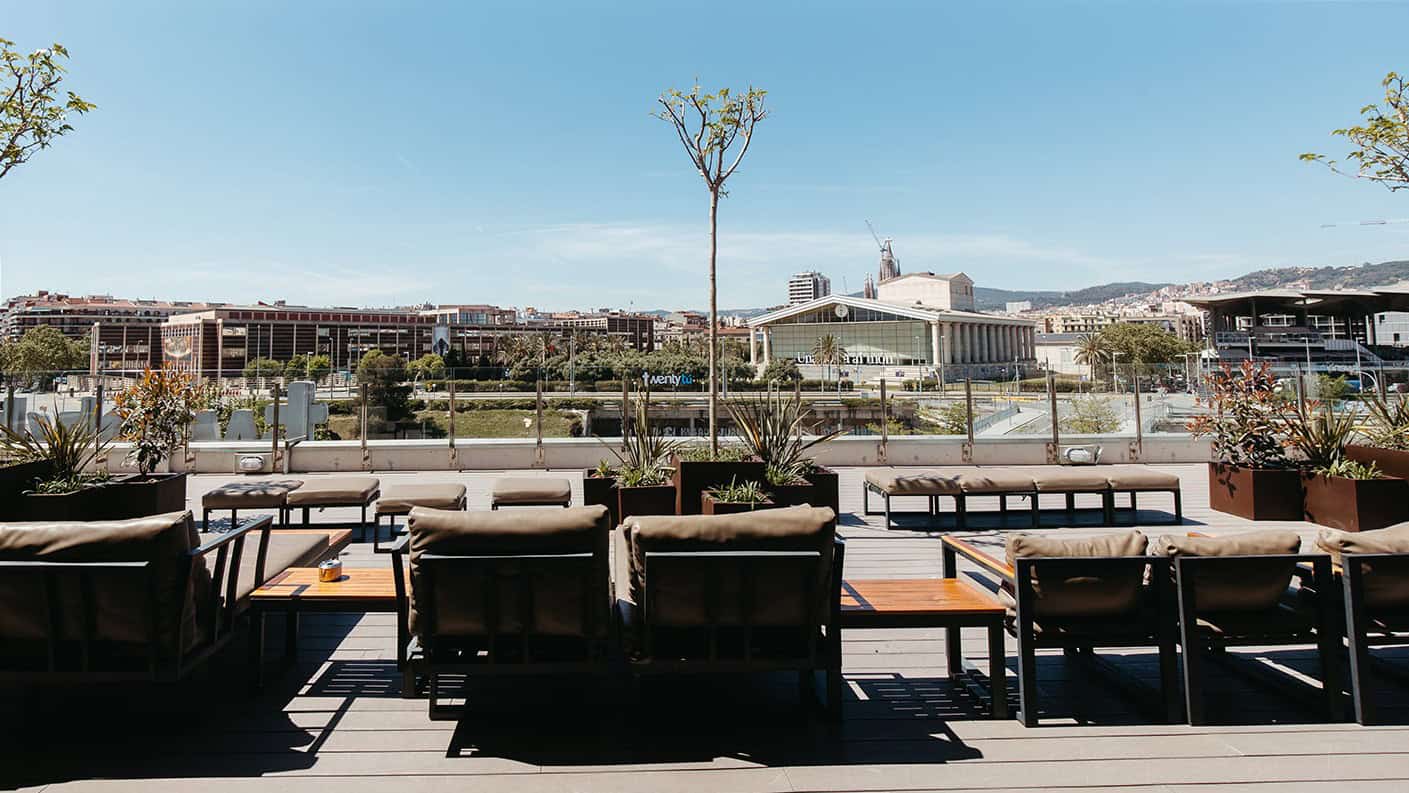 Terraza de TwentyTú con mesas y sofás al aire libre con vistas panorámicas de Barcelona.